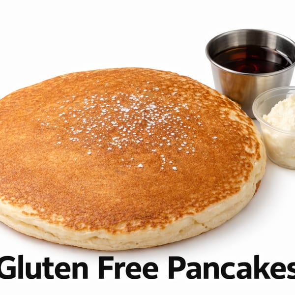A large, golden-brown gluten-free pancake dusted with powdered sugar, served with syrup and butter.