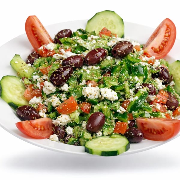 A vibrant Greek salad with tomatoes, cucumbers, olives, and feta cheese on a white plate.