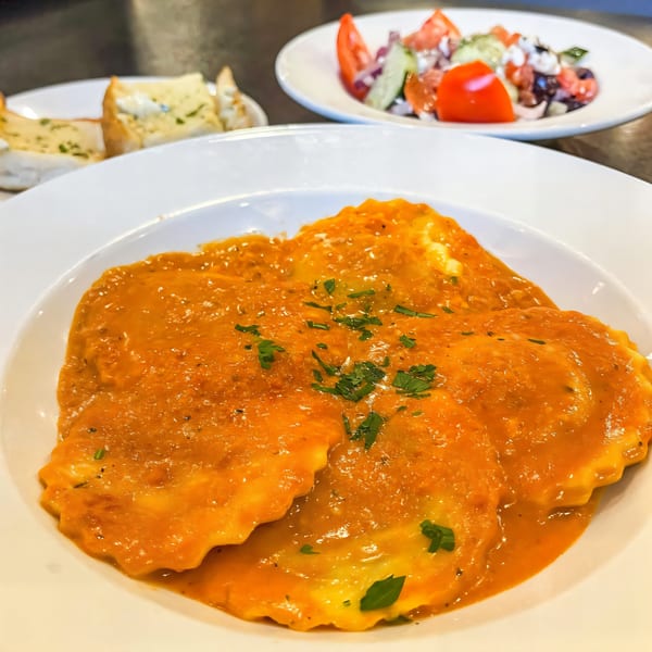 Ravioli with orange sauce and parsley, with garlic bread and salad in the background at JP's Family Restaurant.