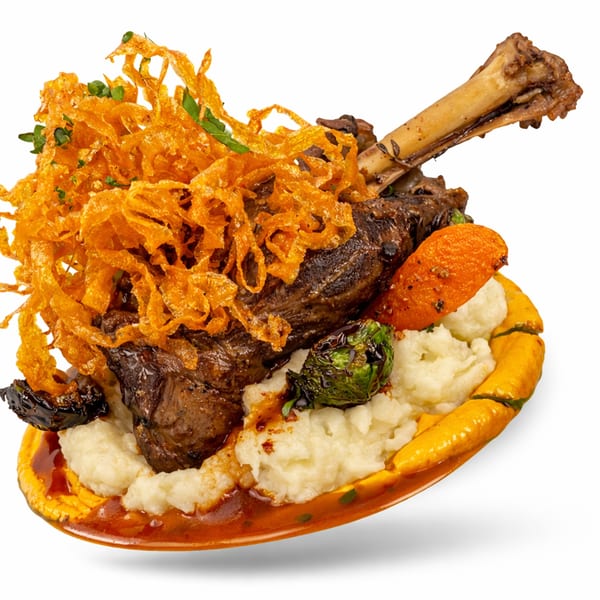 Braised lamb shank with mashed potatoes, roasted carrots, Brussels sprouts, and crispy fried onions.